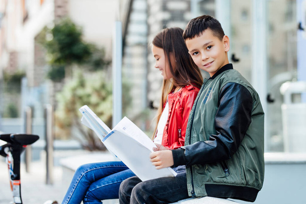 Deux enfants vont à l'école pour gyroscooters. Écoliers modernes en uniforme scolaire lisant des livres ensemble
. - Photo, image