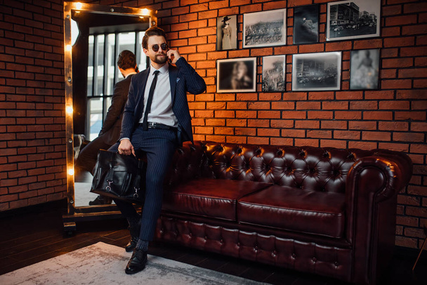 Handsome businessman stay near sofa with phone on hand in luxury apartament. - Fotó, kép