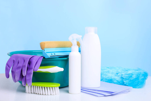 Διαφορετικά προϊόντα καθαρισμού σπιτιού σε μπλε φόντο. - Φωτογραφία, εικόνα
