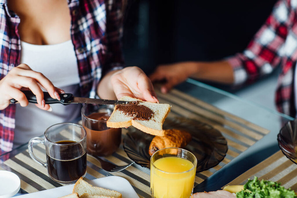Woman hands spreading chocolate butter on the bread in the morning breakfast on table. - Foto, Bild