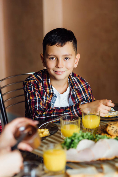 Foto de menino muito pequeno tomar um café da manhã com copo de suco fresco e sanduíche
. - Foto, Imagem