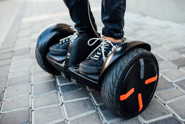 Man legs riding electric mini hoverboard in park. Close up leg photo. - 写真・画像