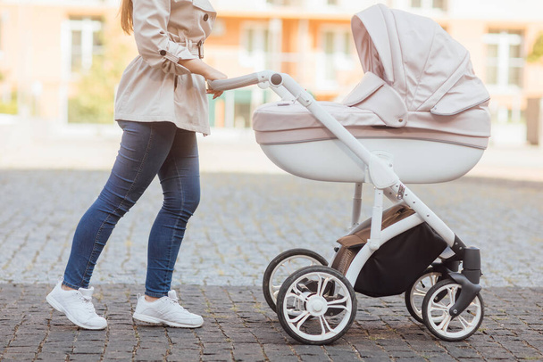 Family, motherhood and people concept - close up of mother with child sleeping in stroller walking at summer park. - 写真・画像