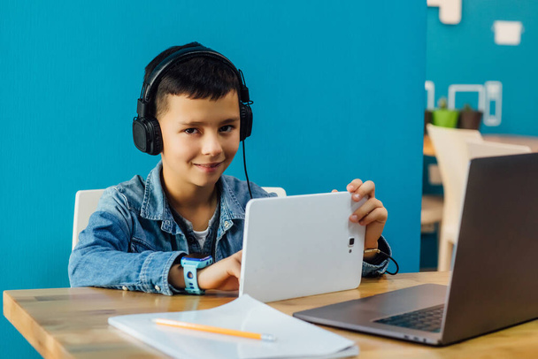Boy sitting on the room in headphone, near him laptop. Education, knowledge time. - Zdjęcie, obraz