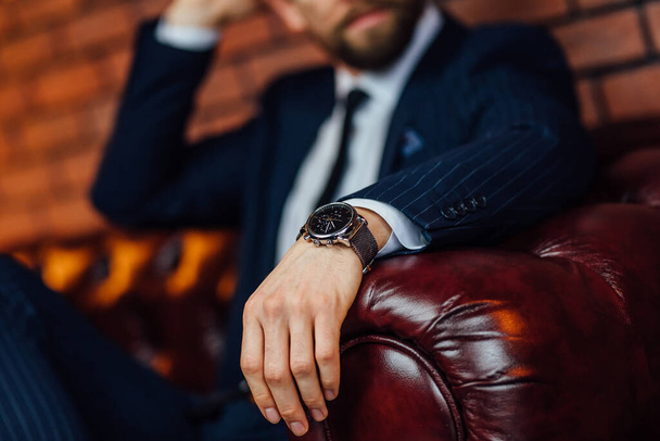 Closeup watch on hand businessman, he sit on sofa and checking time on watch, dark tone. - Фото, зображення