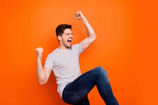 Profile photo of crazy cool funny guy yelling open mouth raise fists sport game match rejoicing best win team wear casual striped t-shirt jeans isolated bright orange color background - 写真・画像