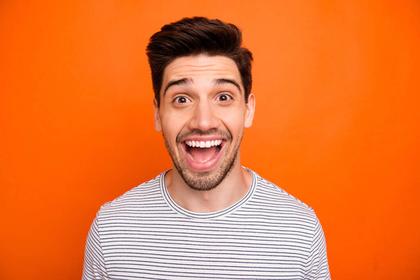 Closeup photo of crazy funky energetic guy open mouth best excited feelings emotions listen good news wear casual striped t-shirt isolated bright orange color background - 写真・画像