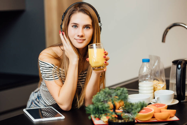 Woman in modern kitchen drinking smoothie. Healthy lifestyle. - Фото, зображення
