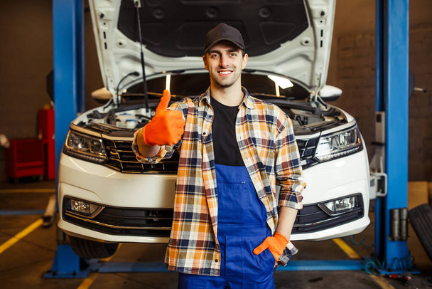 portrait of handsome mechanic showing thumb up and smiling at the camera the modern service center - Photo, image