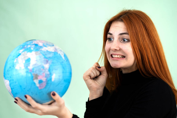 Portrait of a sad worried young woman holding geographic globe of the world in her hands. Travel destination and planet protection concept. - Fotografie, Obrázek