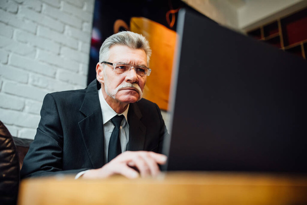 Senior mature or  business man having a lunch break in a coffee shop and working on his laptop. - Φωτογραφία, εικόνα