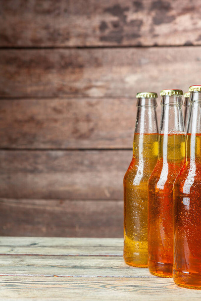 Fresh beer in glass bottles on wooden background - Foto, imagen
