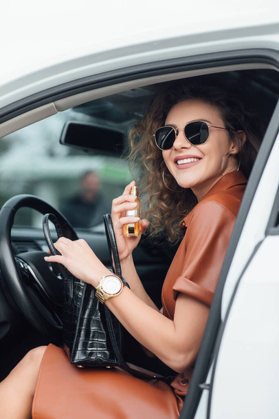 Living in a business world. Portarit of businesswoman using her perfume in the car. - Foto, afbeelding