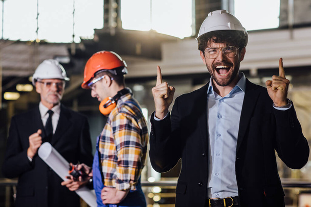 Youngand happy business owner in helmet meet with foreman in new building. - Φωτογραφία, εικόνα