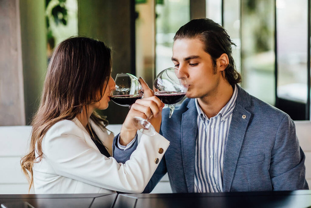 Portrait of young couple drinking red wine on broodershaft and enjoying this time. - Photo, Image