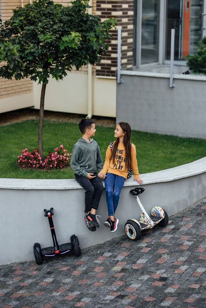 Small children couple on vacation having fun after driving electric scooter through the city. - Fotó, kép