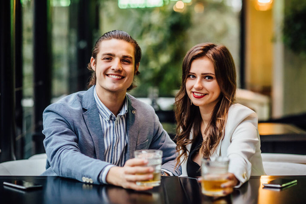 Lovely concept, pretty young and cheerful couple with drinks on hands spend time at modern restaurant. - Fotó, kép