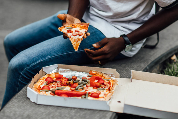 Close up photo. Food concept, man eating pizza on street. - Foto, afbeelding