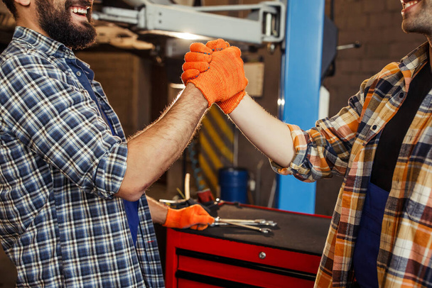 обрезанный снимок двух коллег, пожимающих руки в перчатках на заправке
 - Фото, изображение