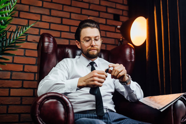 Business man resting on armchair in luxury room. Handsome man smoking cigar or iqos. - Foto, immagini