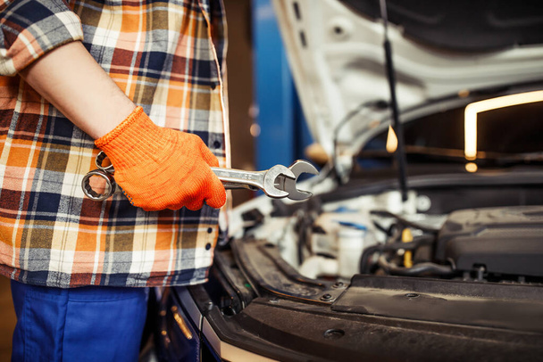 close up of mechanic working with car engine and holding wrenches - Foto, imagen