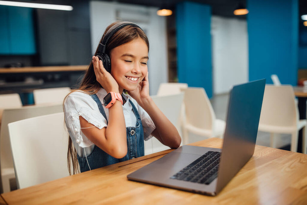 Girl using a laptop computer and headphone at modern school. - Fotoğraf, Görsel