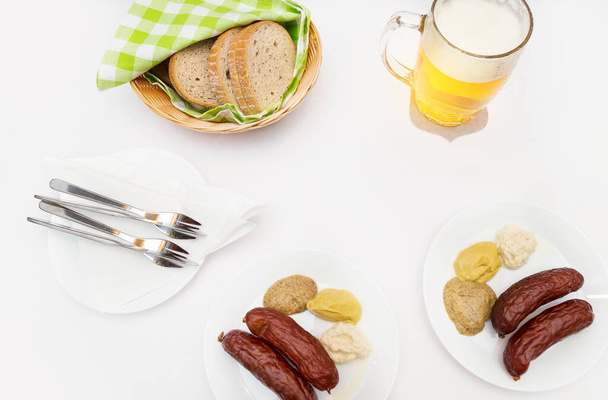 Weißer Tisch mit Würstchen, Senf, Meerrettich, Brot und Bier - Foto, Bild