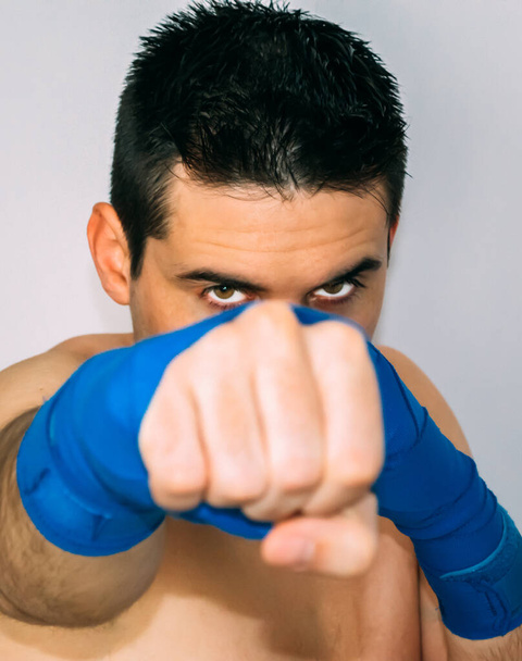 boxeador com um olhar intenso, ligaduras azuis. Punho desfocado. Conceito desportivo
 - Foto, Imagem