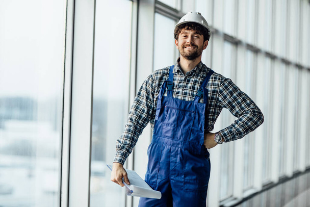 Happy builder, young man architect in hard hat holding folder. - Фото, зображення