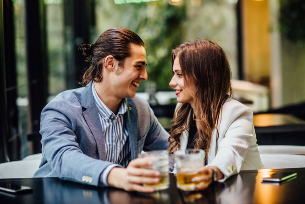 Lovely concept, pretty young and cheerful couple with drinks on hands spend time at restaurant. - Foto, Imagem