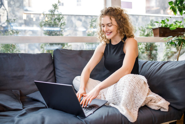 Cute blonde woman spending time at home on weekend, working with laptop and smiling. - Photo, image