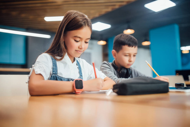 Two kids writing homework at modern classroom. - Zdjęcie, obraz
