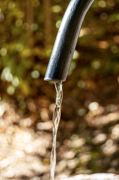 Extreme close-up of fresh water flowing from an outdoor faucet in mountain (Italian Alps), Italy, Europe - Photo, Image