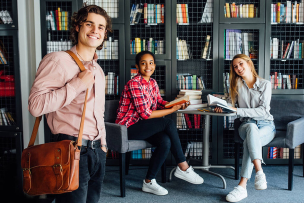 Three young and happy students spend time with books at meeting library room. - Foto, afbeelding