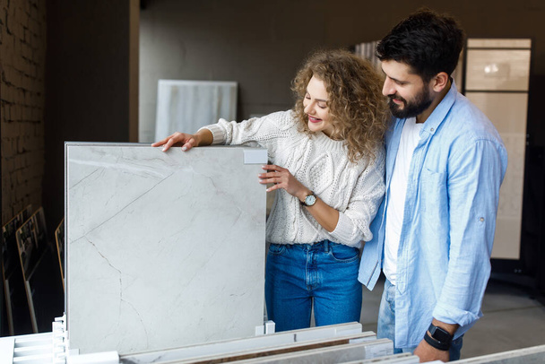 Happy young couple pointing at ceramic tile for bathroom floor in store. - Foto, Bild