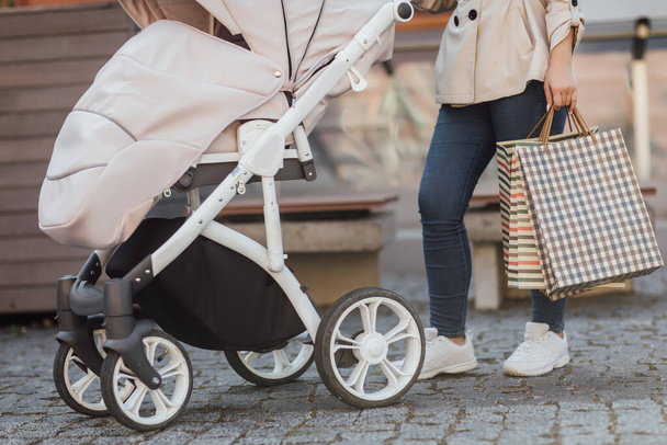 Close up photo, shopping with baby in stroller, woman holding shopping bags. - Foto, imagen