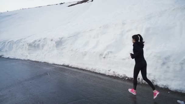 山の深い雪の中で練習精力的な女性のジョギングを決定しました - 映像、動画