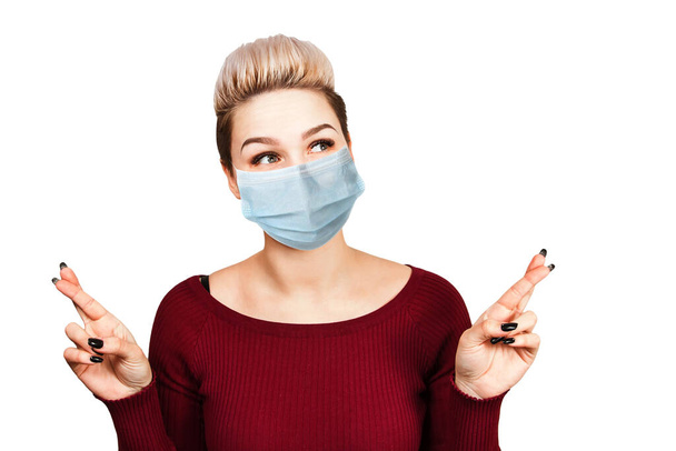Portrait young woman with cross fingers. wearing protective face mask prevent virus infection, white isolated background. - Foto, Imagem