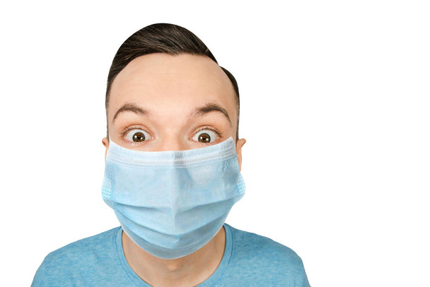 Young guy with wide eyes, Unhappy, wearing a protective face mask prevent virus infection on white isolated background. - Zdjęcie, obraz