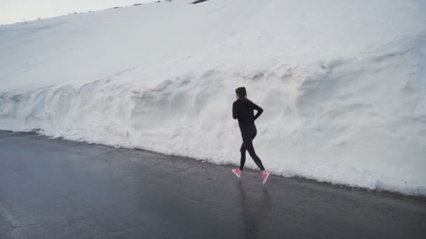 Einsamer Jogger mit leuchtend rosa Laufschuhen sprintet in Schneekorridor in den bulgarischen Bergen - Filmmaterial, Video