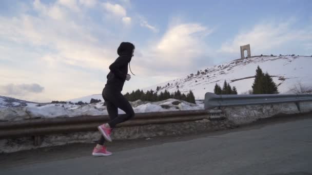 Energetische Profi-Läuferin beim Training in den verschneiten Bergen bei Sonnenuntergang - Filmmaterial, Video