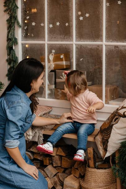 beautiful little girl with mother at home during Christmas - Photo, Image