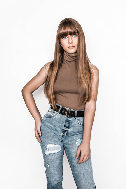 Fashion portrait of beautiful young girl with smooth hair. Girl in blouse and jeans. Clothing and bangs hairstyle. High fashion look. School teenager. Glamour stylish hipster young model - Fotó, kép