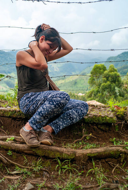 Hnědá a latinskoamerická žena, usmívající se se zavřenýma očima a držící si vlasy na pahorku zemědělství - Fotografie, Obrázek