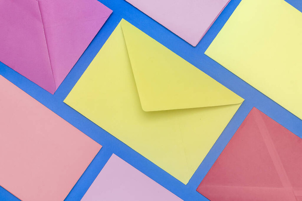 Enveloppes et papiers colorés disposés en diagonale sur fond bleu
 - Photo, image