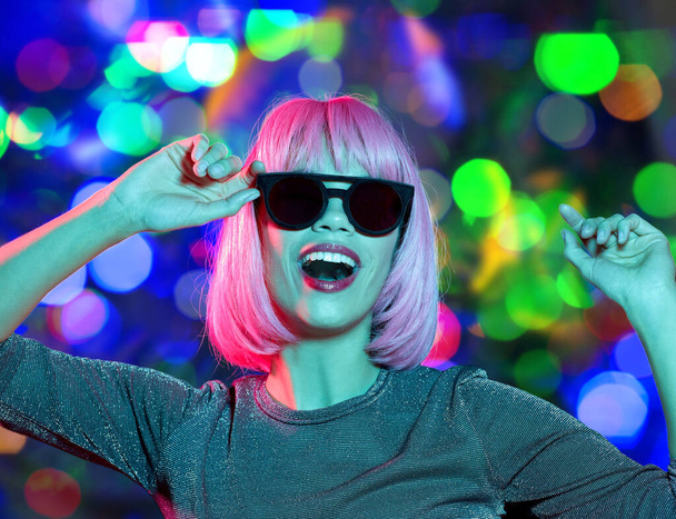 happy woman in pink wig and sunglasses dancing - Foto, afbeelding