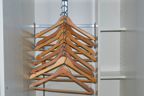 Cabides de pano de madeira sem roupas em um guarda-roupa
 - Foto, Imagem