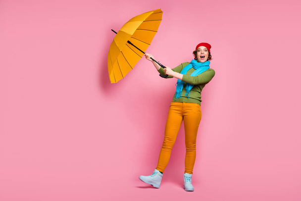 Full body photo excited girl travel trip her shine umbrella fly wind air she try catch scream wow omg wear blue red headwear pullover winter pants isolated pink color background - Photo, image