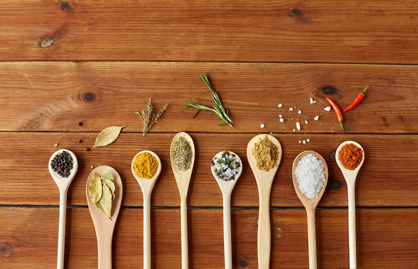 spoons with spices and salt on wooden table - Foto, Imagen