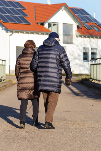 ηλικιωμένο ζευγάρι περπατά στο δρόμο με νεόδμητα σπίτια - Φωτογραφία, εικόνα